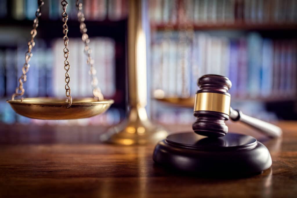 Close up of a judges gavel, scale, and books in the background