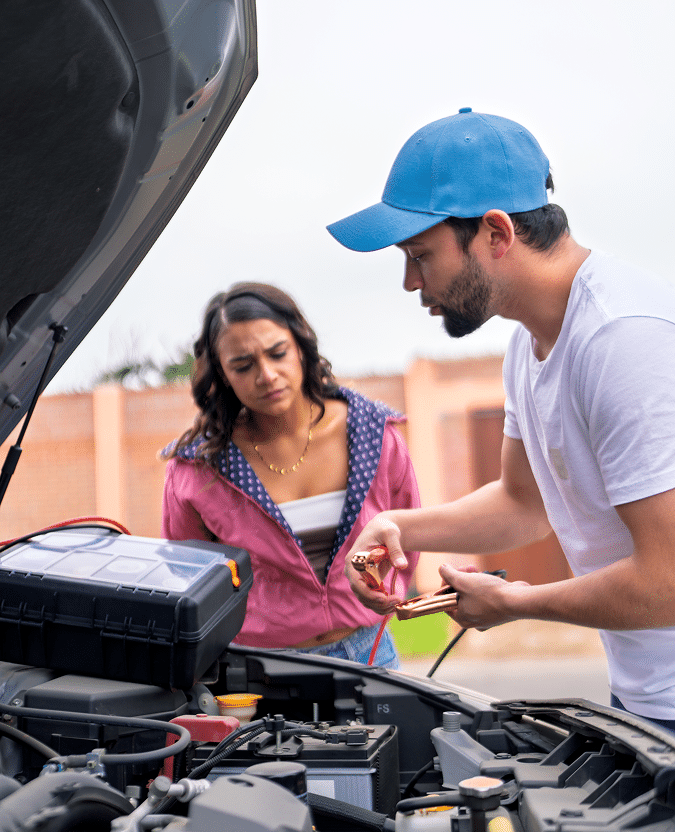 A man and woman charging a car battery
