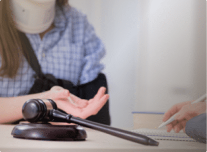 An injured person in an arm sling and neck brace in front of a judges gavel