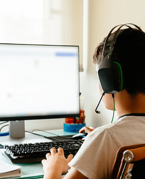 A child with a headset on playing at the computer