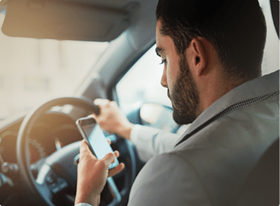 A man texting and driving looking at his phone