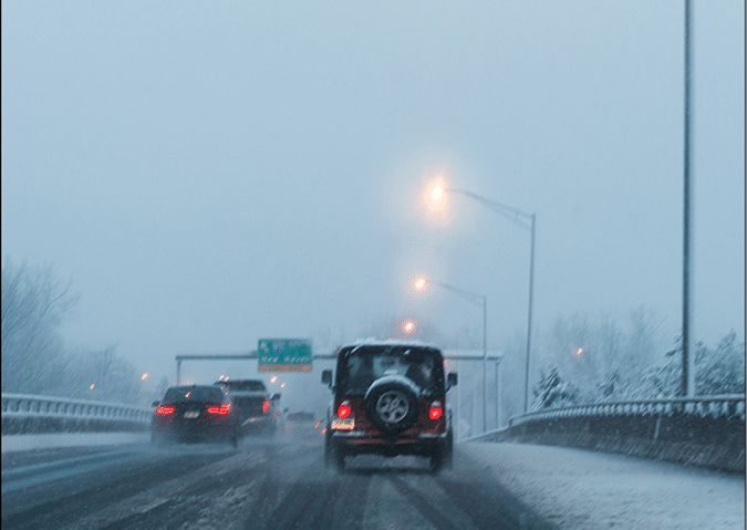 Cars driving down a highway in the snow