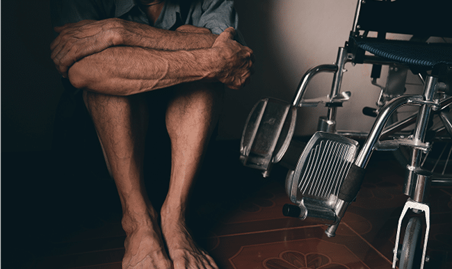 A man sitting on the ground next to a wheelchair