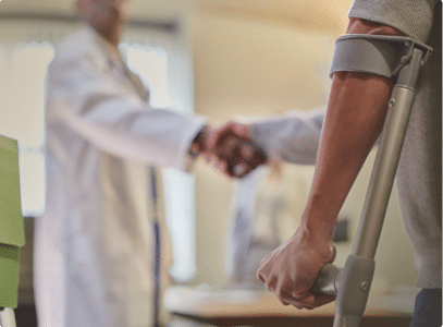 a doctor shaking the hands of a person holding a crutch
