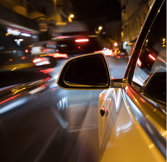 close up of a drivers side mirror with a blurry night city in the background