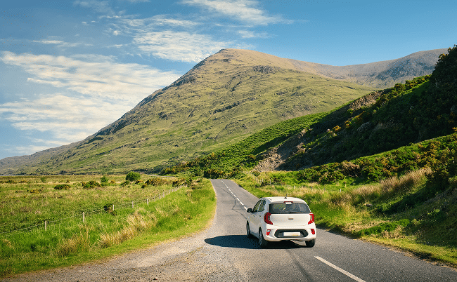 a white care driving down an empty road in the mountains