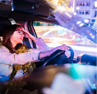 a woman looking stressed in the driver seat at night