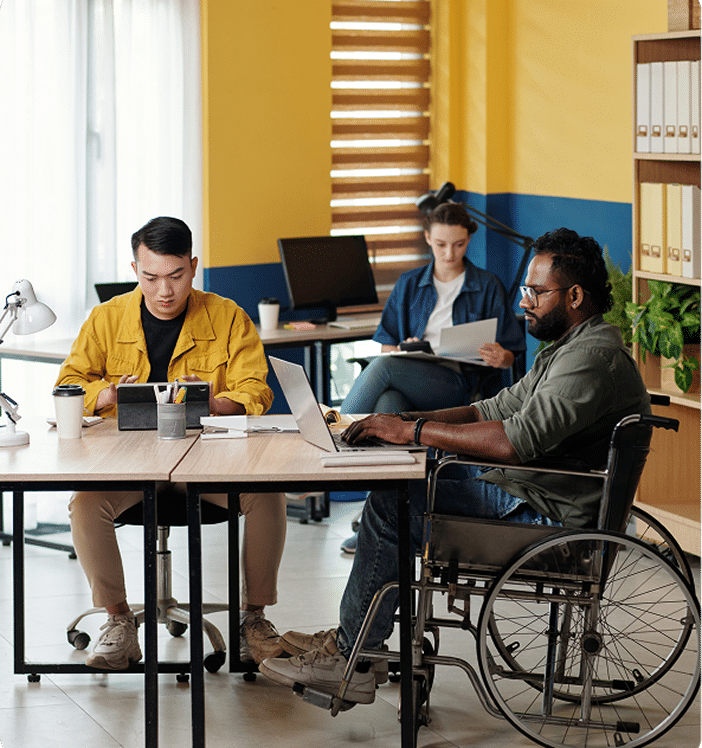 A team of 3 people working at a desk in the office